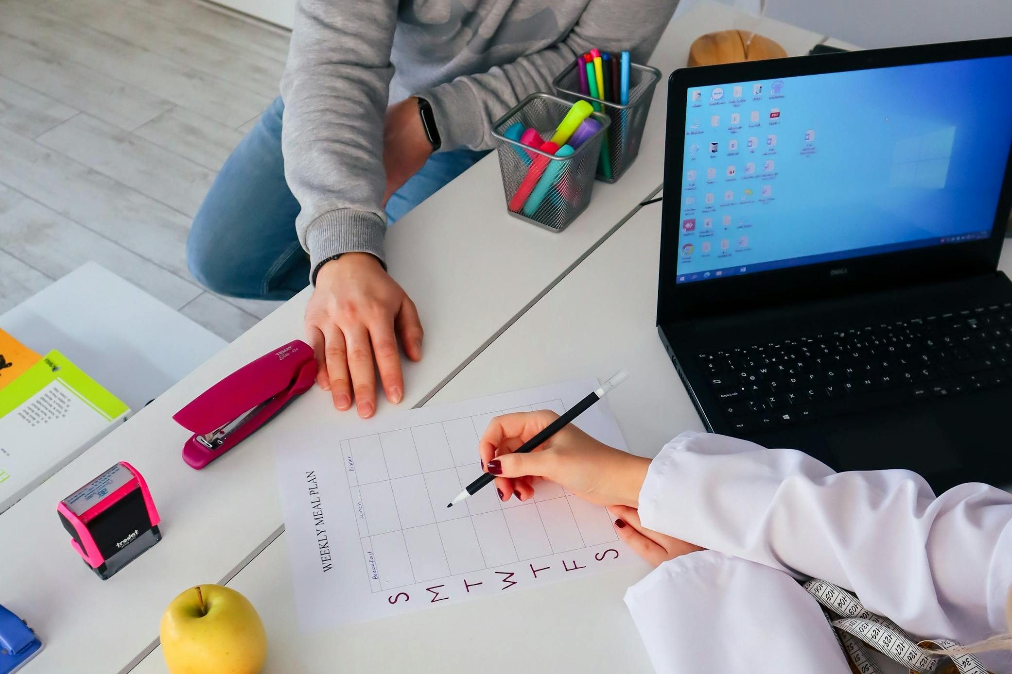 A nutritionist and a patient discuss a weekly meal plan in a modern office setting.